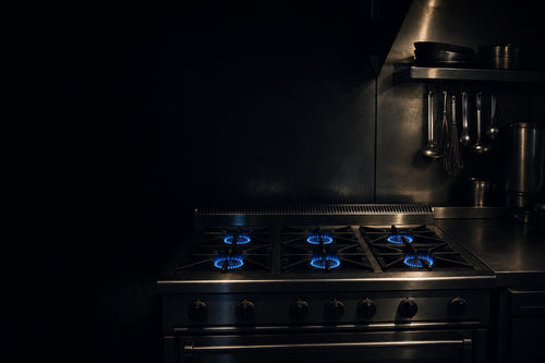 Deep blue gas flames on a commercial range with dark moody kitchen background